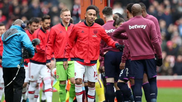 Arsenal and West Ham United players give each other a fist bump before the season was shut down.