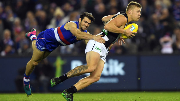 Dog fight: Collingwood's Jordan de Goey attempts to shrug off a flying tackle from Easton Wood.