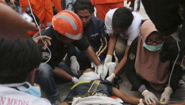 Rescuers check a survivor at restaurant building damaged by a massive earthquakes and tsunami in Palu.