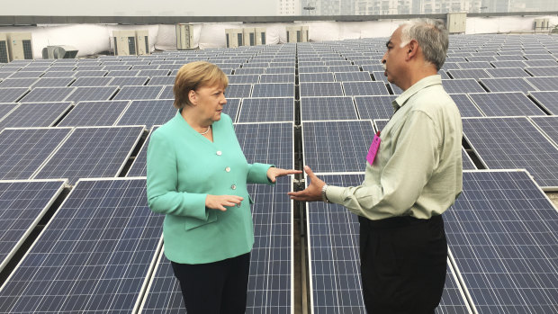 German Chancellor Angela Merkel speaks with an officer as she looks at solar panels on the roof of a metro station in New Delhi, India.