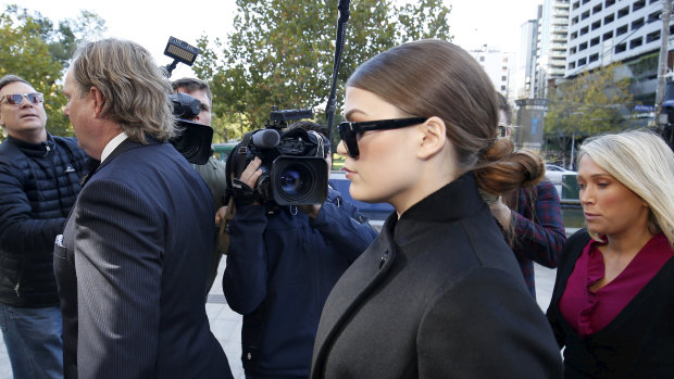 A press pack surrounds Belle Gibson as  she makes her way into court.