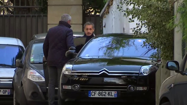 Former French president Nicolas Sarkozy (right) leaves his residence in Paris on Wednesday for a second day of interviews with investigators.