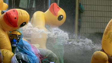 Pro-democracy protesters take cover with inflatable ducks as police fire water cannons during an anti-government rally near the Parliament in Bangkok.