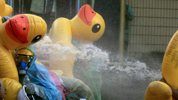 Pro-democracy protesters take cover with inflatable ducks as police fire water cannons during an anti-government rally near the Parliament in Bangkok.