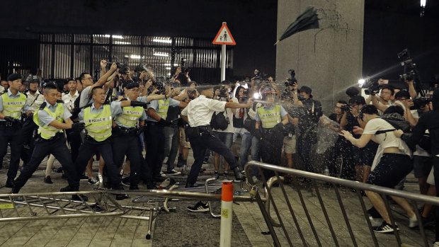 Police officers use pepper spray against protesters.