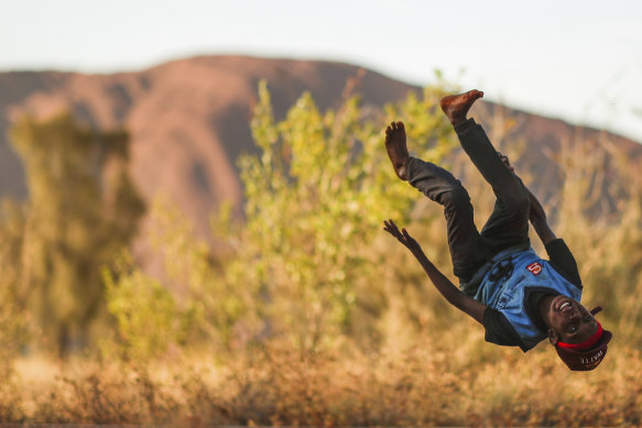 A boy performs a flip while waiting for celebrations to begin after Uluru was closed to climbers.