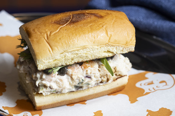 Prawn roll, a sawn-off brioche roll sandwiching creamy crustacean and black tahini mayo.