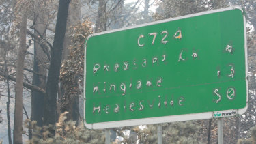 A road sign for Pheasants Creek, Kinglake and Healesville damaged by the fires. 