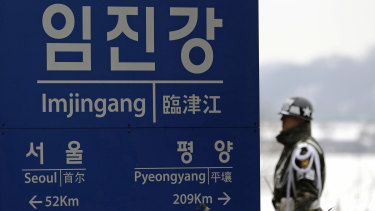 A South Korean soldier stands near a signboard showing the distance to Pyongyang and to Seoul from Imjingang Station in Paju, South Korea.