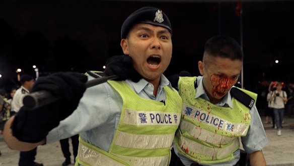 A Hong Kong police officer being assisted by his colleague after clashing with protesters.