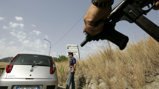 An Italian police officer holds a submachine gun at a roadblock in 2007 near San Luca, a Calabrese town notoriously known as an organised crime stronghold.