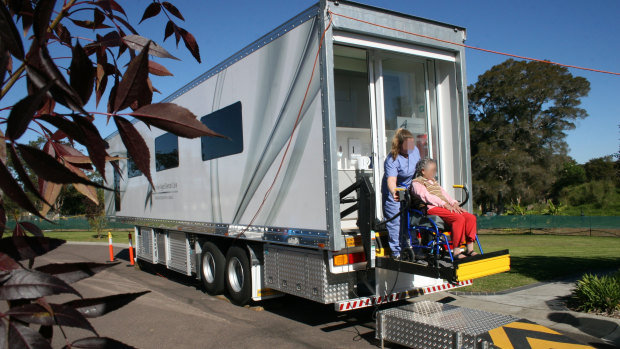 A clinic manager for Australian Aged Dental Care loads an elderly lady into a van outside a retirement home in Wyee in 2012.