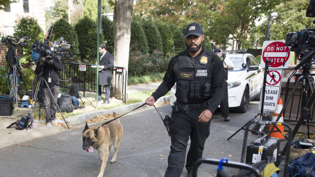An officer with the Uniform Division of the United States Secret Service uses his dog to search a checkpoint near the home of President Barack Obama.