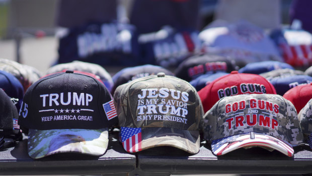 Hats reading, “God, Guns and Trump” and “Jesus is my saviour, Trump is my president” are sold at a campaign rally.