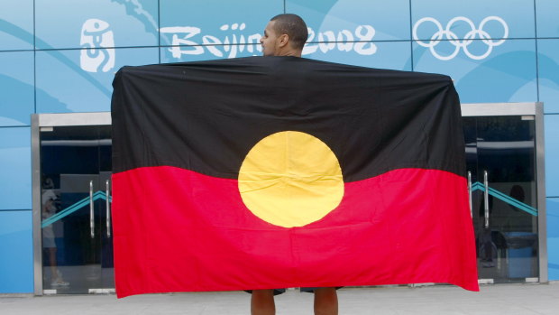 Mills showing his pride in the Aboriginal flag at the Beijing Olympics.