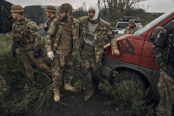 A Ukrainian soldier helps a wounded fellow soldier on the road in the freed territory in the Kharkiv region, Ukraine.
