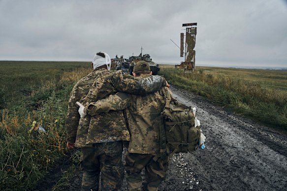 A Ukrainian soldier helps a wounded comrade on the road near Kharkiv. 
