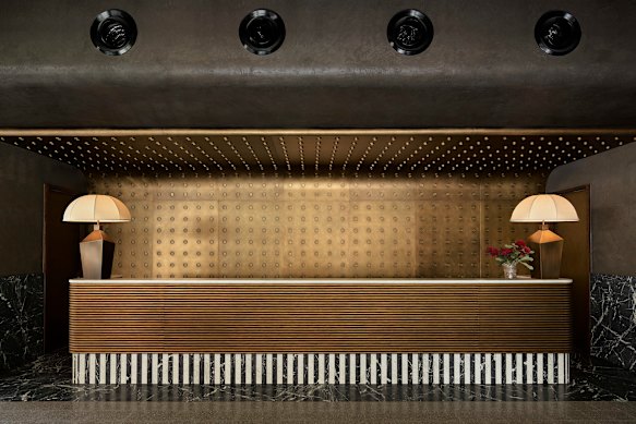 Os hóspedes fazem check-in na imponente recepção dourada no lobby do Hannah St Hotel.