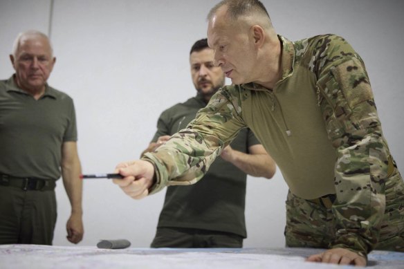 Ukrainian President Volodymyr Zelensky (centre) and Commander-in-Chief Oleksandr Syrsky (right) look at a map while visiting Sumy, Ukraine, in mid-August.