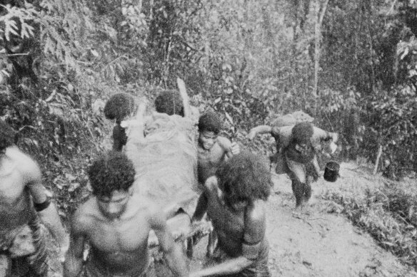 Native Papuan bearers carry an Australian casualty through thick jungle at Eora Creek, 1942.