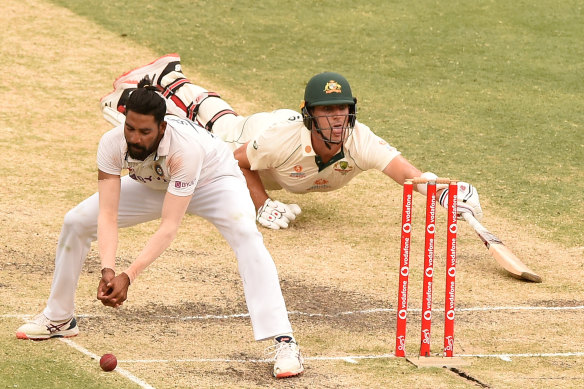Mohammed Siraj of India fields as Pat Cummins of Australia makes his ground.