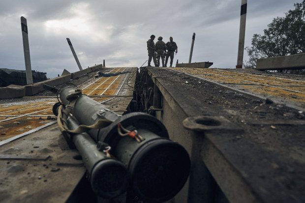 Ukrainian soldiers stand on a destroyed bridge in Izyum, Kharkiv region. Ukraine has made some strategic victories in the war.