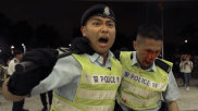 A Hong Kong police officer being assisted by his colleague after clashing with protesters.