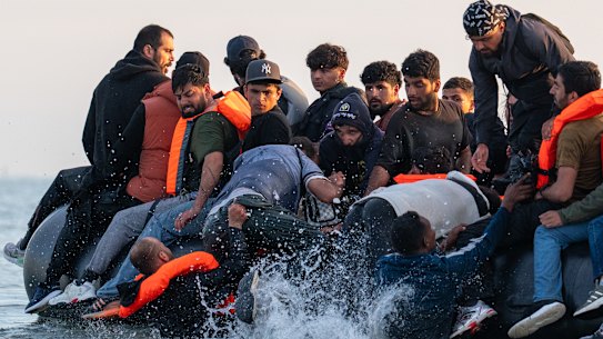 Migrants board a small boat bound for the United Kingdom off the shoreline of Gravelines beach in Calais, France, on July 17.