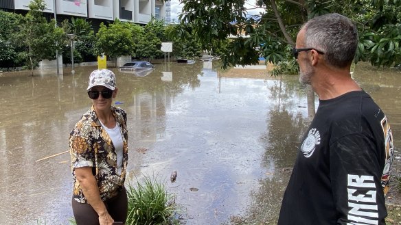Jason and Rebecca Petzke look at cars swamped by floodwater at West End in 2022.