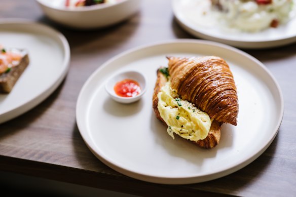 Croissant de huevos revueltos con dukkah casera, hierbas y mermelada de chile.