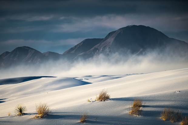 White sand dunes with black mountains behind them