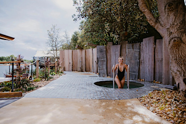 A woman getting into a small cold plunge pool outdoors