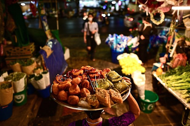 A food vendor carries a tray full of delicacies along an alley at Pak Khlong Talat market in Bangkok.