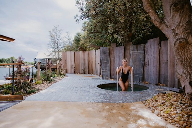 A woman getting into a small cold plunge pool outdoors