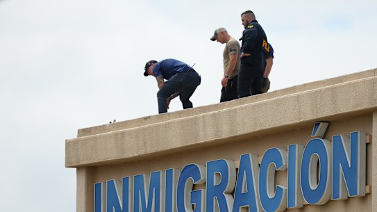 Investigators on the roof of a building near the scene of a shooting at a US Immigration and Customs Enforcement facility in Dallas on Wednesday.