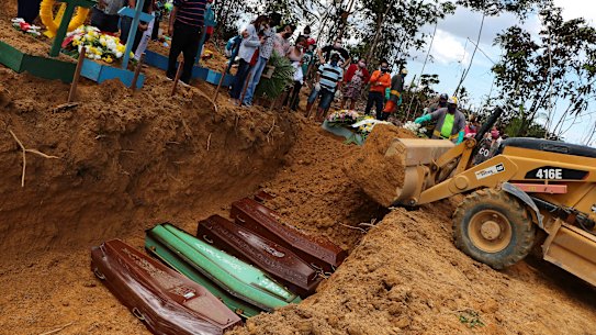 A backhoe buries coffins in a common pit at the Nossa Senhora Aparecida cemetery in Manaus.