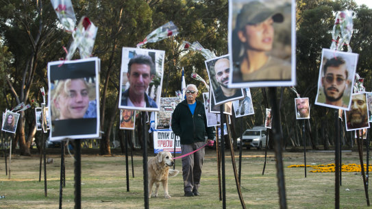 A man walking his dog views photos of people who were killed during Hamas’ attack on the Nova festival at the site.