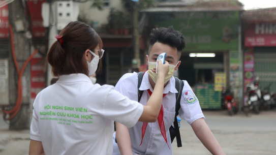 A student is scanned for temperature before entering Dinh Cong secondary school in Hanoi, Vietnam.