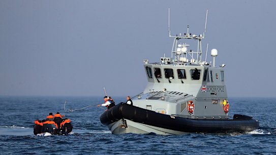 A Border Force vessel assists a group of people thought to be migrants on board from their inflatable dinghy in the English Channel.