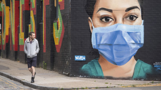 A man walks past mural depicting a nurse wearing a face mask in the Shoreditch area of east London.