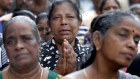 Sri Lankan Catholics pray on a road during a brief holly Mass held outside the exploded St Anthony's Church. 