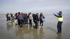 A group of people thought to be migrants is escorted up the beach in Dungeness, Kent, on Thursday.