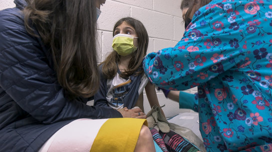 Alejandra Gerardo, 9, looks up to her mother, Dr Susanna Naggie, as she gets the first of two Pfizer COVID-19 vaccinations during a clinical trial for children at Duke Health.