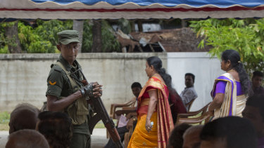 A soldier stands guard amid Catholics attending Mass outside St Joseph's church in Thannamunai, Sri Lanka, on Tuesday.