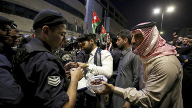 Protesters offer sweets to police officers standing guard in Amman on Tuesday.