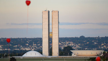 Artists from Brasilia hold a performance with red balloons in honour of victims of coronavirus outside the Brazilian Senate and Congress on Monday.