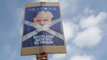 A protester holds up a banner as people gather to protest the visit by US President Donald Trump and first lady Melania Trump, in Turnberry, Scotland, on Saturday July 14.