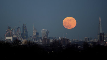 The moon rises over the London skyline.