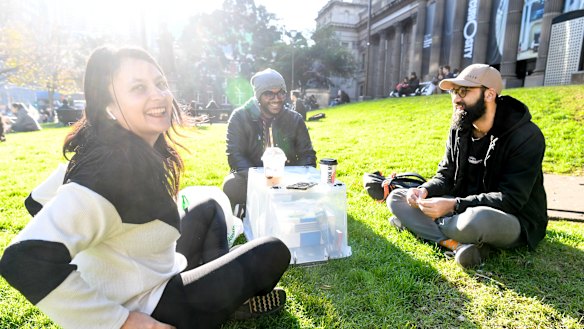 Carlton D’Silva (right), pictured having a coffee with friends Akshaya and Kenneth outside the State Library, said he had seen some people not abide by social distancing, but none within his smaller group of friends.