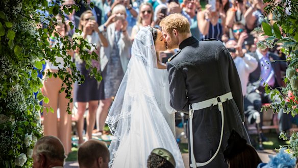 Meghan Markle and Prince Harry kiss on the steps of St George Chapel. 